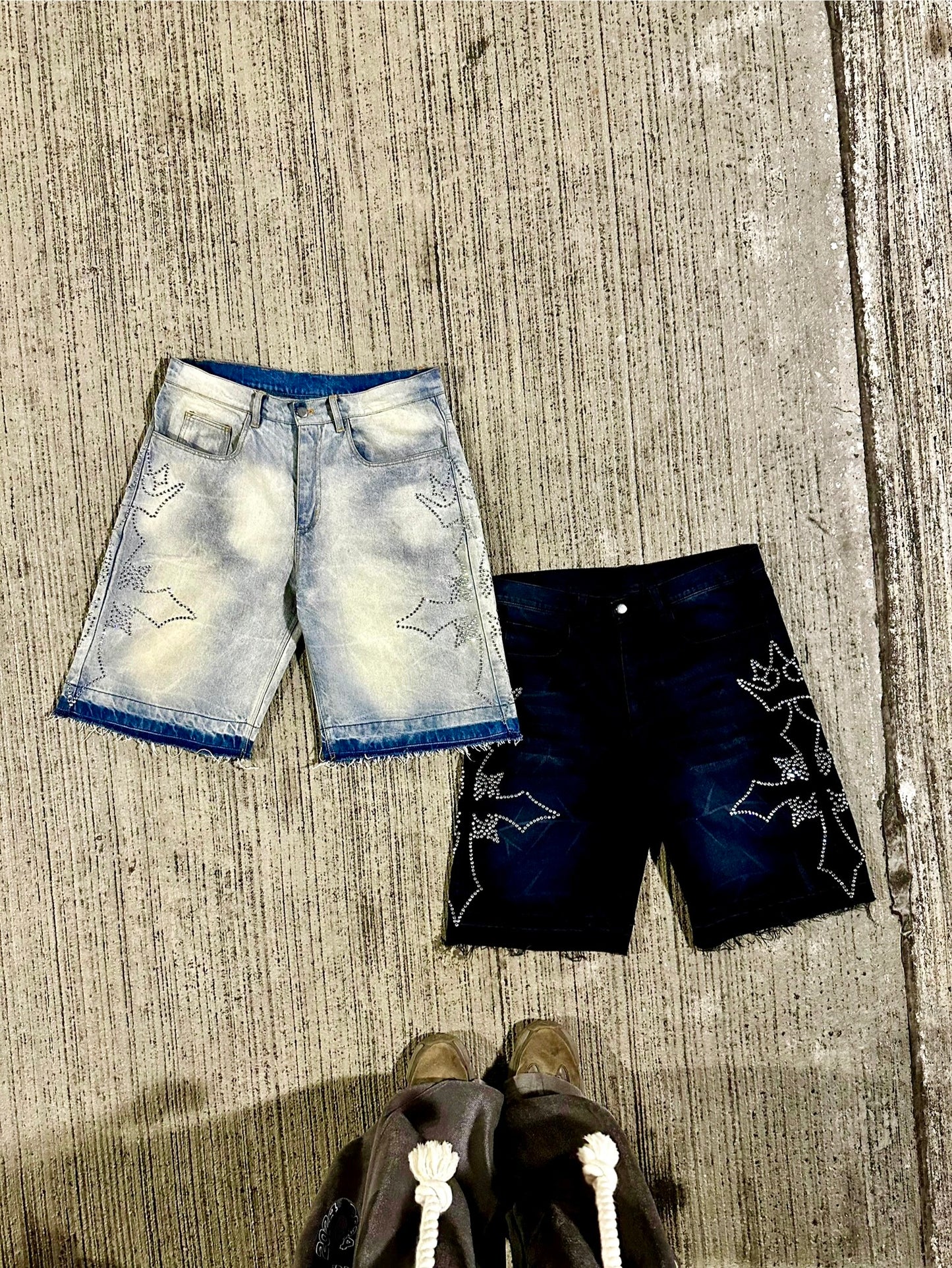 Two pairs of shorts, one light blue and one black, on a textured surface.